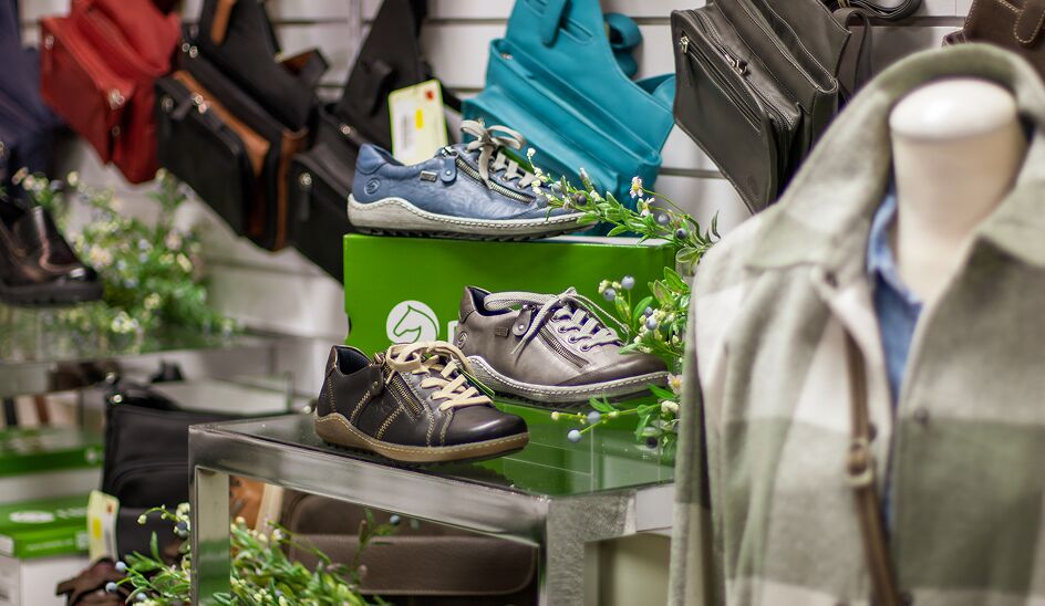 Shoe display with purses on the wall in the background. A mannequin in the foreground. 